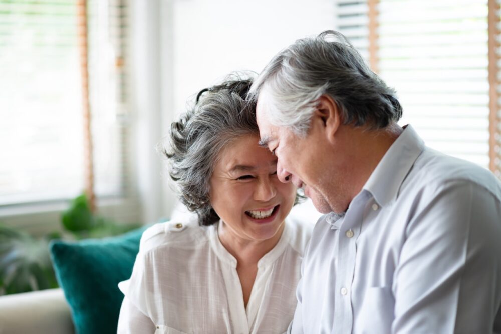 Healthy Asian older people laughing and relaxing at their house together. Happy smiling Elderly man and woman celebrating Anniversary. Joyful senior couple in love. Showing an active lifestyle that could be led at Anchors New Home development coming soon to Stevenage exclusively for the over 55s.